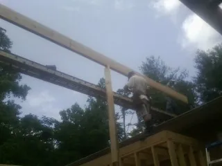 Carpenter setting a ridge beam over a new addition frame — Ice Dam Removal by Roofing Brothers in Wainscott
