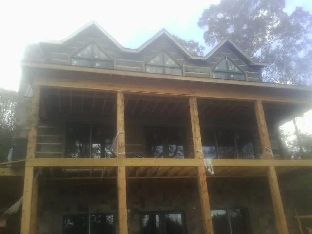 Dormers and porch framing on a large log home under construction — Roof Coating work by our crew in Wainscott