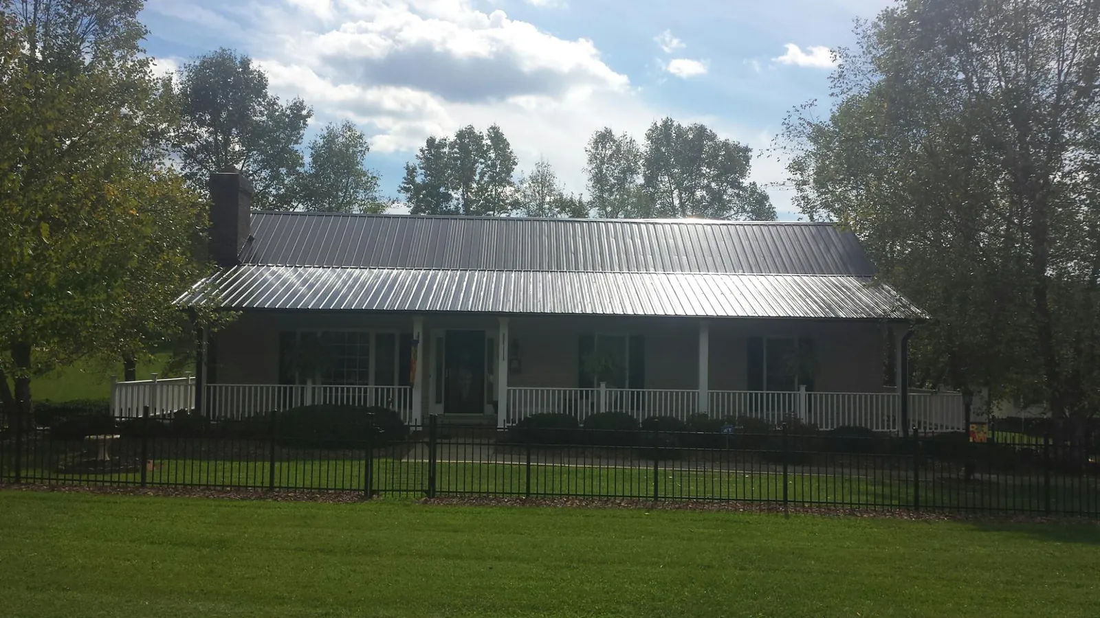 Gray metal roof on a brick ranch with a full width front porch — Gutter Guard Installation work by our crew in Wainscott