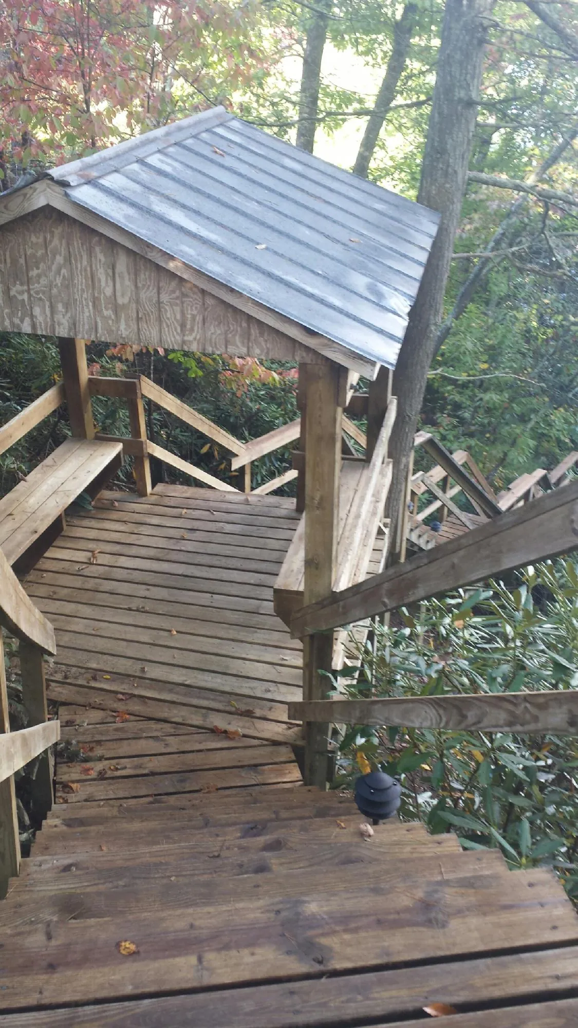 Metal roofed shelter over wooden steps on a wooded walkway — Skylight Repair & Installation work by our crew in Wainscott