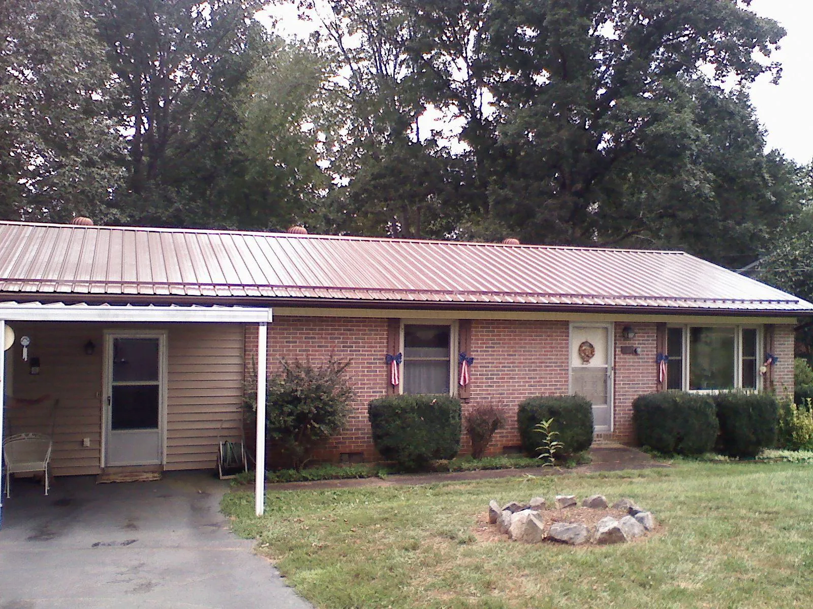 Bronze metal roof and carport on a brick ranch home — Roof Repair work by our crew in Wainscott