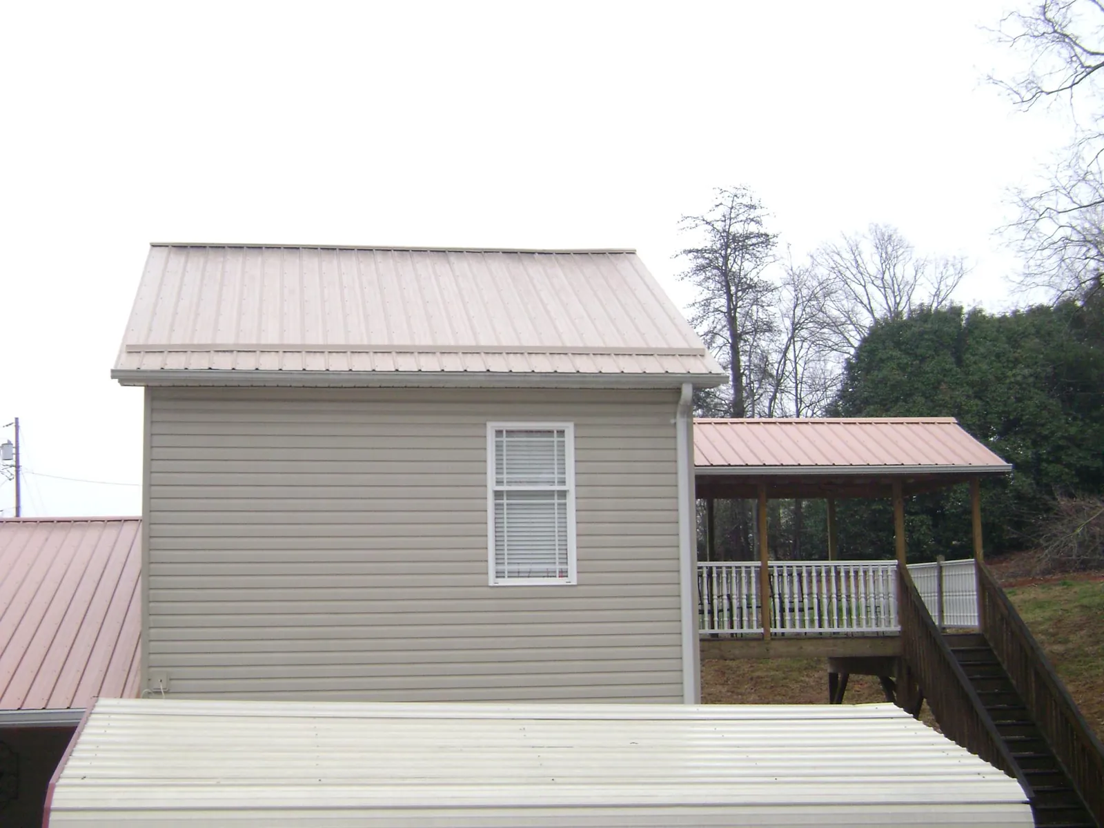 Tan metal roofs on a two story addition and attached porch, from a Roof Replacement job in Wainscott