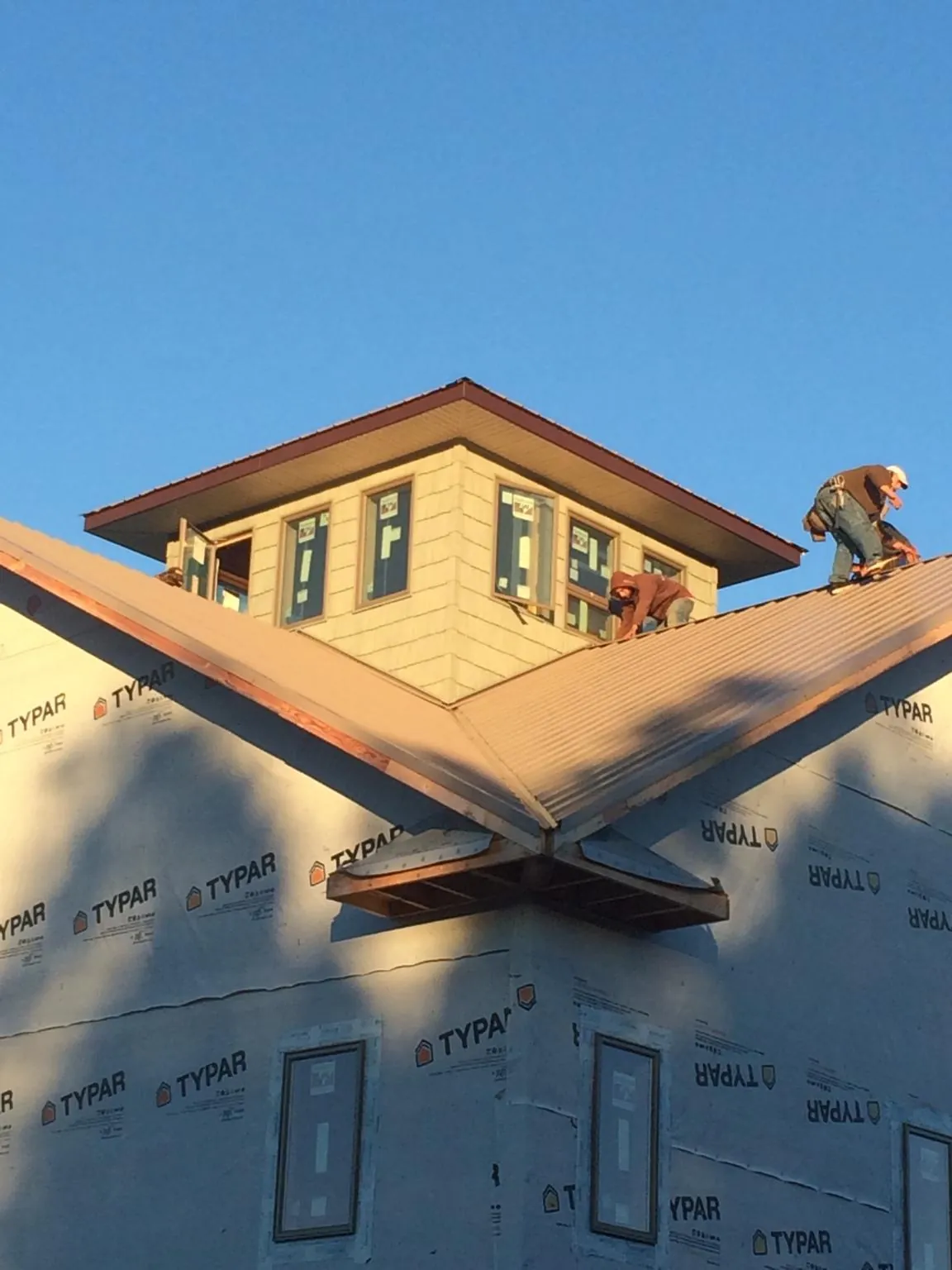 Roofers working around a rooftop cupola on a new metal roof at sunset — Roof Waterproofing in Wainscott by Roofing Brothers